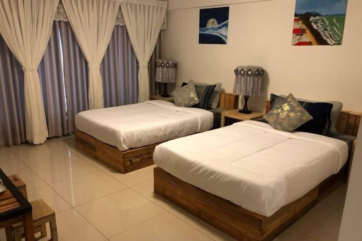 A hotel room with two wooden beds, a nightstand, a lamp, and a painting on the wall.