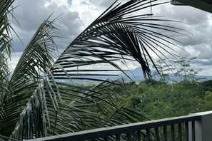 A balcony with palm trees and a view of a lush landscape. - Brown Street Cafe and Vacation House (Batangas City)