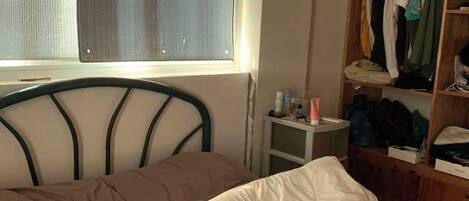 Quarto com cama, janela, armário e mesinha de cabeceira.