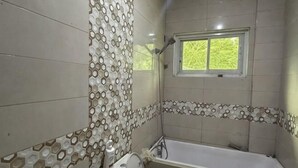 Un baño con bañera, ducha y ventana.
