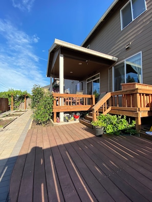 A wooden deck with a covered porch, potted plants, and a clear sky. - Beautiful 4BR Home in E Vancouver 30+ Day Stays Near PDX, Costco & Hospitals (Vancouver)