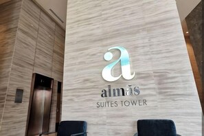 A reception area with a logo for 'almás Suites Tower' and an elevator. - Almas Suites Homestay ByStay (Iskandar Puteri)