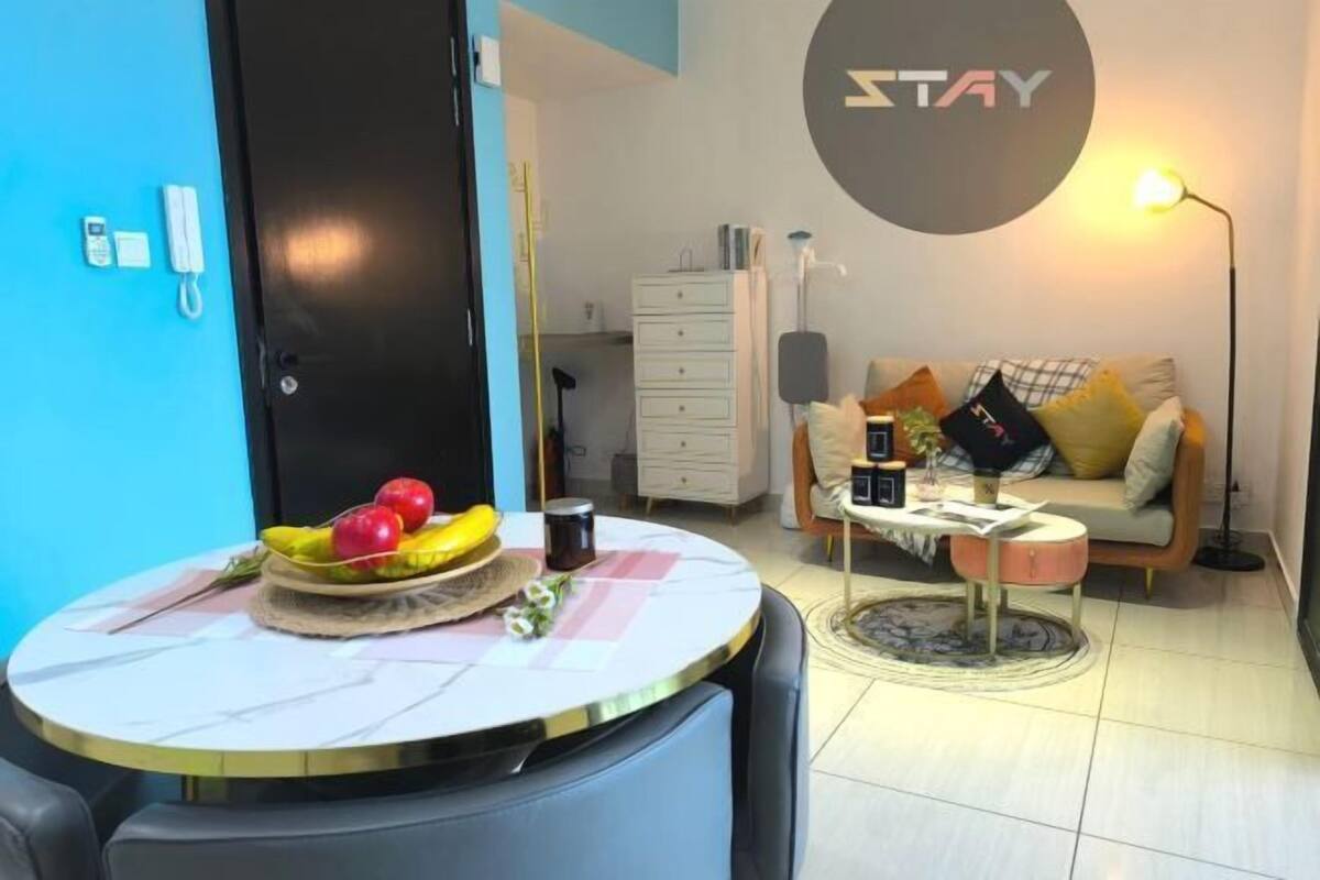 A room with a round table, a sofa, a lamp, and a wall sign.