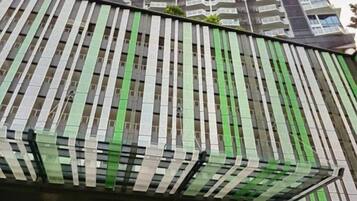 Une façade d’immeuble avec des rayures verticales vertes et blanches, une ligne de toit incurvée et une série de fenêtres.