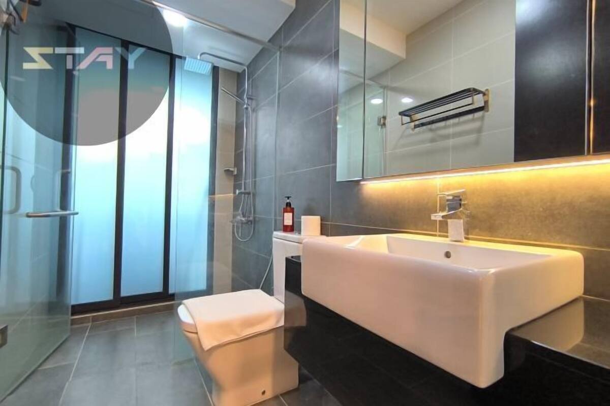 A modern bathroom with a large mirror, a white sink, and a glass shower enclosure.