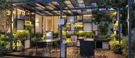 Un espace extérieur aménagé en terrasse, avec une pergola, des sièges et des plantes en pot.