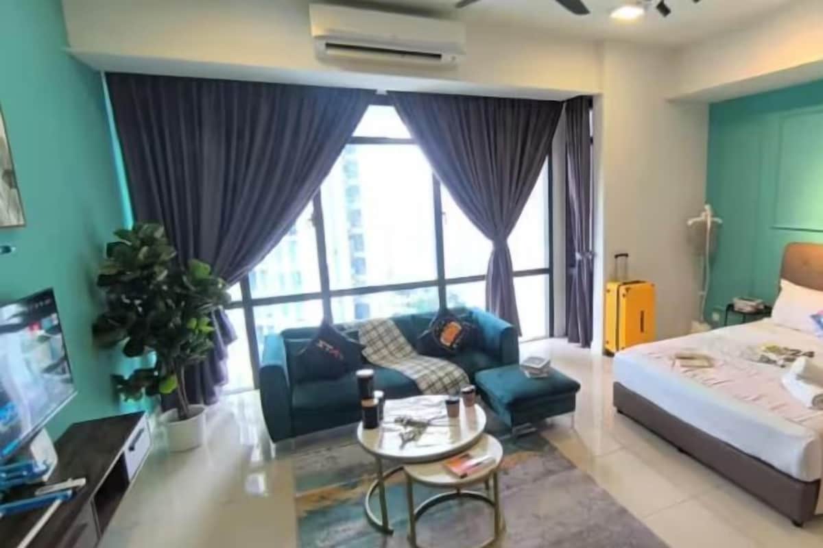 A modern hotel room with a large bed, a sofa, a coffee table, and a TV.