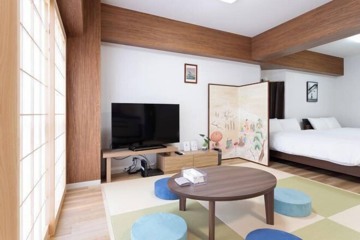 Une chambre d’hôtel moderne avec un grand lit, une télévision, un bureau avec une chaise et une petite table ronde.