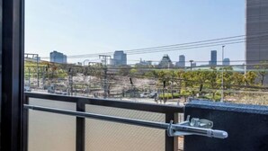 Udsigt fra en balkon med gelænder, en by i baggrunden og en bygning med glasfacade.