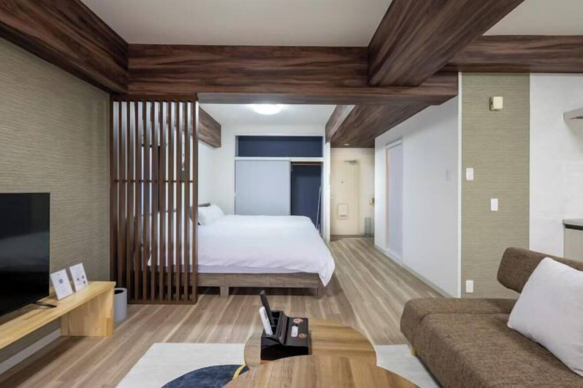 Une chambre d’hôtel avec un lit, une télévision, un canapé et un plancher en bois.