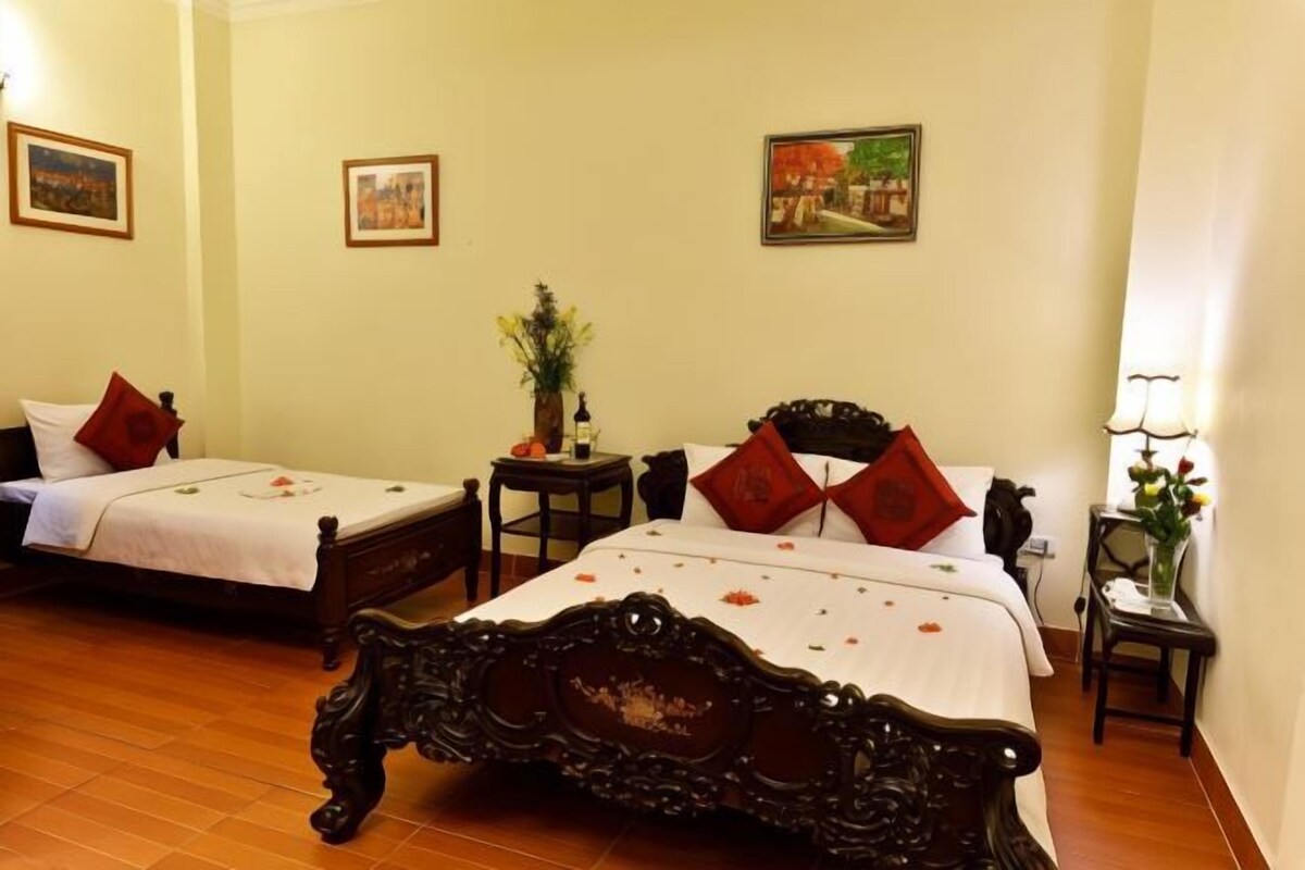 A hotel room with two beds, a wooden floor, and wall-mounted artwork.