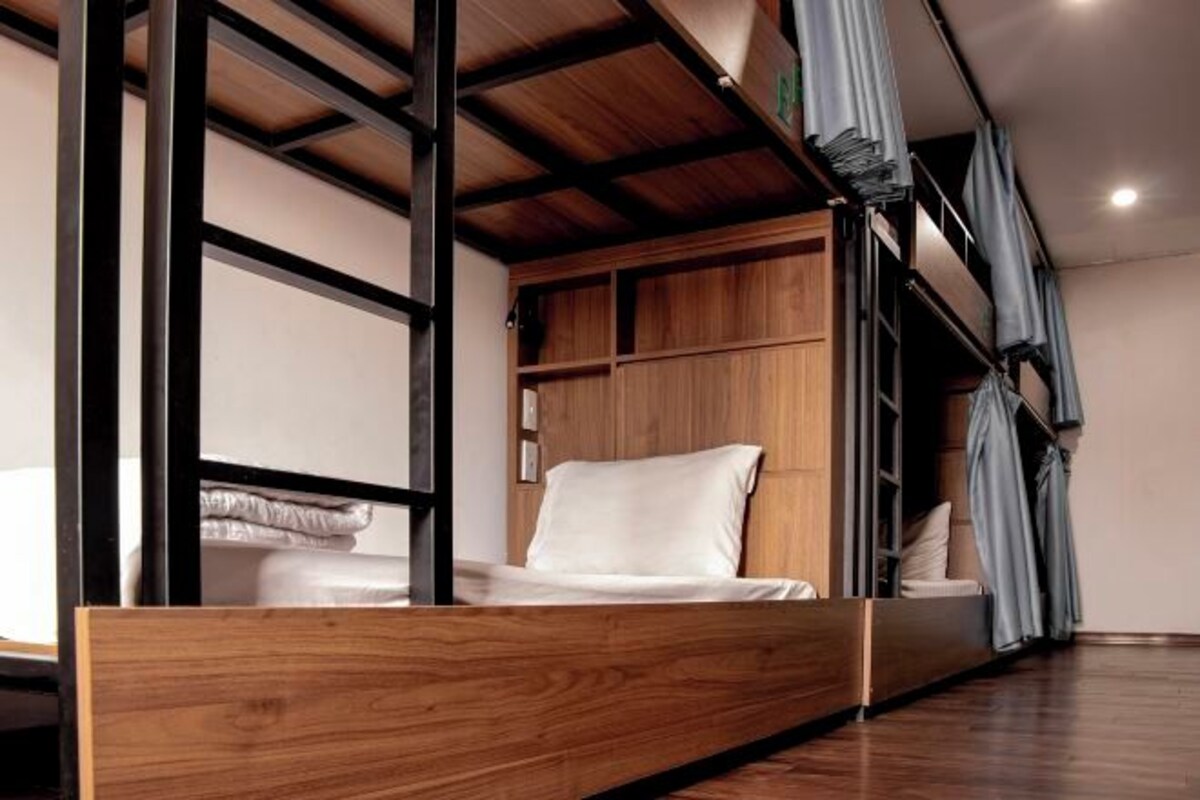 A bunk bed with a wooden frame and a built-in storage unit beneath the upper bunk.