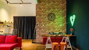 A modern living room with a brick wall, a neon heart decoration, and a red couch. - Manhattan Theme Suite by Nest Home at Austin Heights (Tebrau)