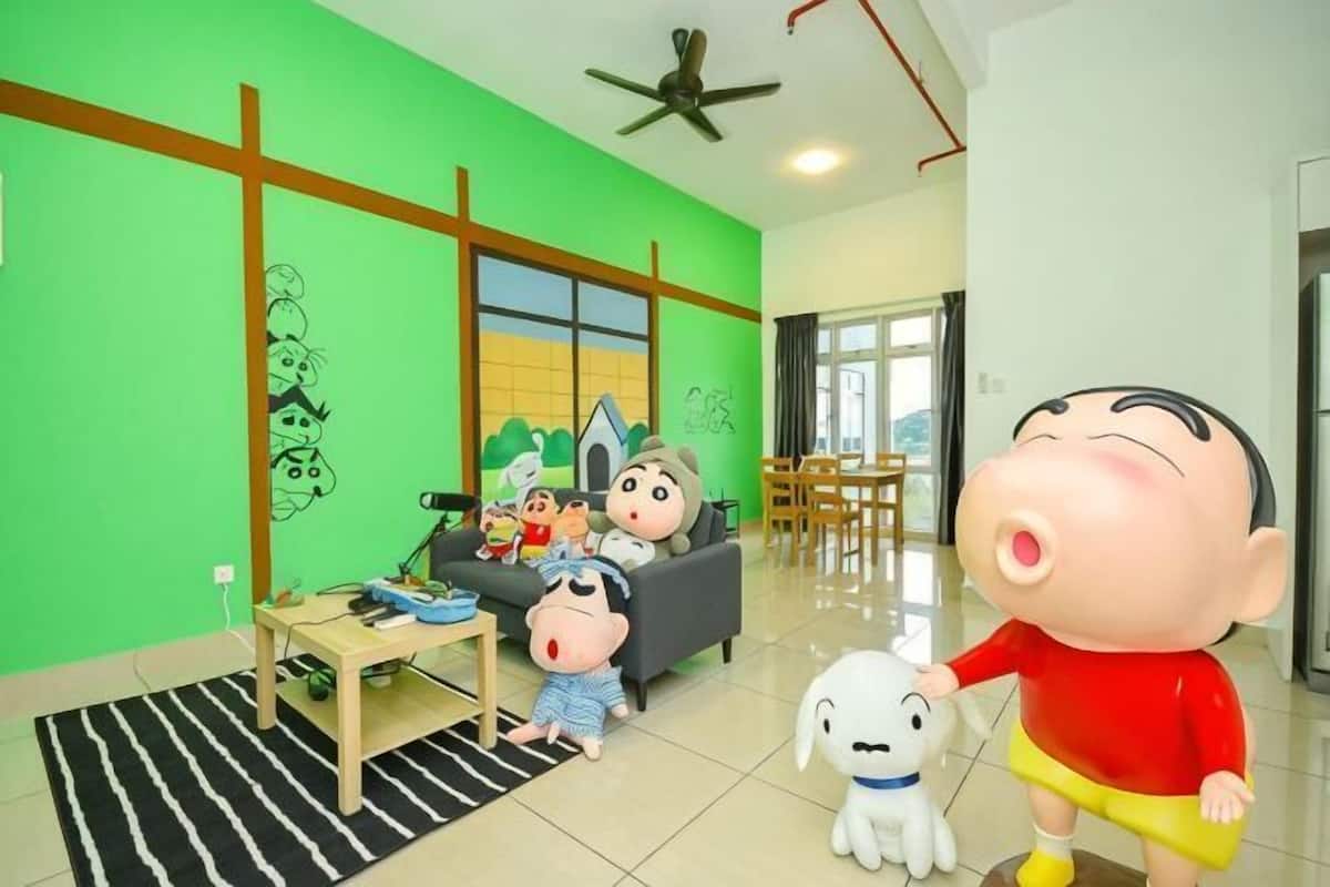 Una sala de estar con una pared verde, un sofá, una mesa de centro y un ventilador de techo.