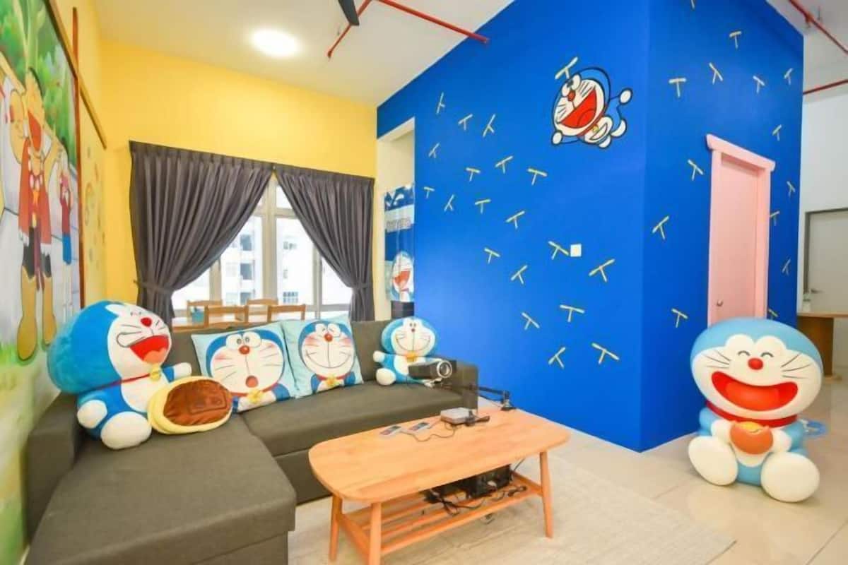 Habitación con sofá, una mesita de centro y decoración en la pared, incluyendo personajes de dibujos animados.