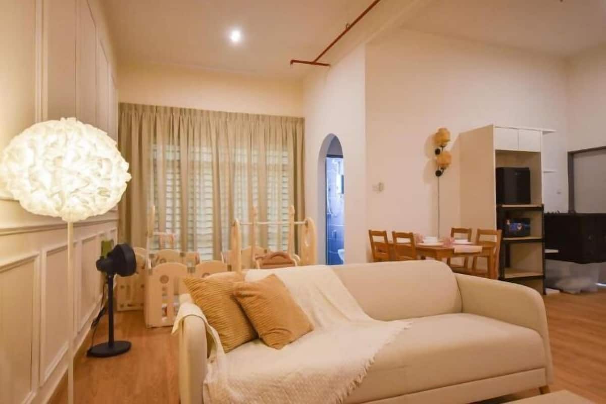 Una sala de estar con un sofá, una lámpara, una mesa de comedor y un televisor.