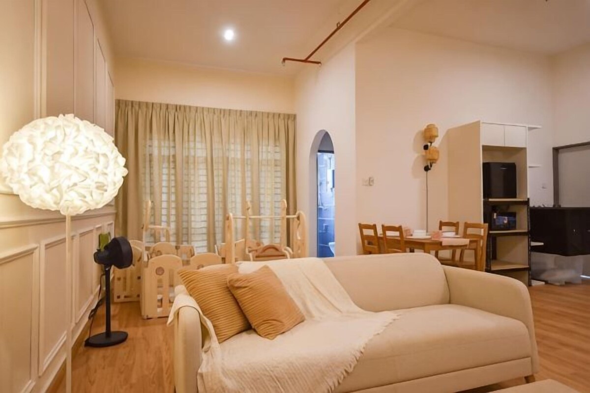 Ein Wohnzimmer mit Sofa, Lampe, Esstisch und Fernseher.
