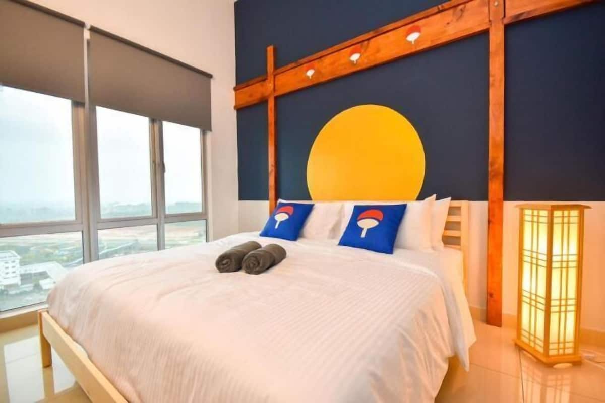 Un dormitorio con cama, almohadas, mesita de noche, ventana y lámpara de pared.
