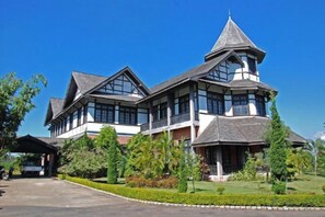 A large, two-story building with a prominent tower, surrounded by well-maintained gardens and a clear sky. - Aureum Palace Hotel & Resort, Pyi Oo Lwin (Pyin Oo Lwin)