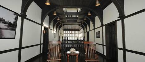 A corridor with arched ceilings and wooden flooring, leading to a bar area with seating.