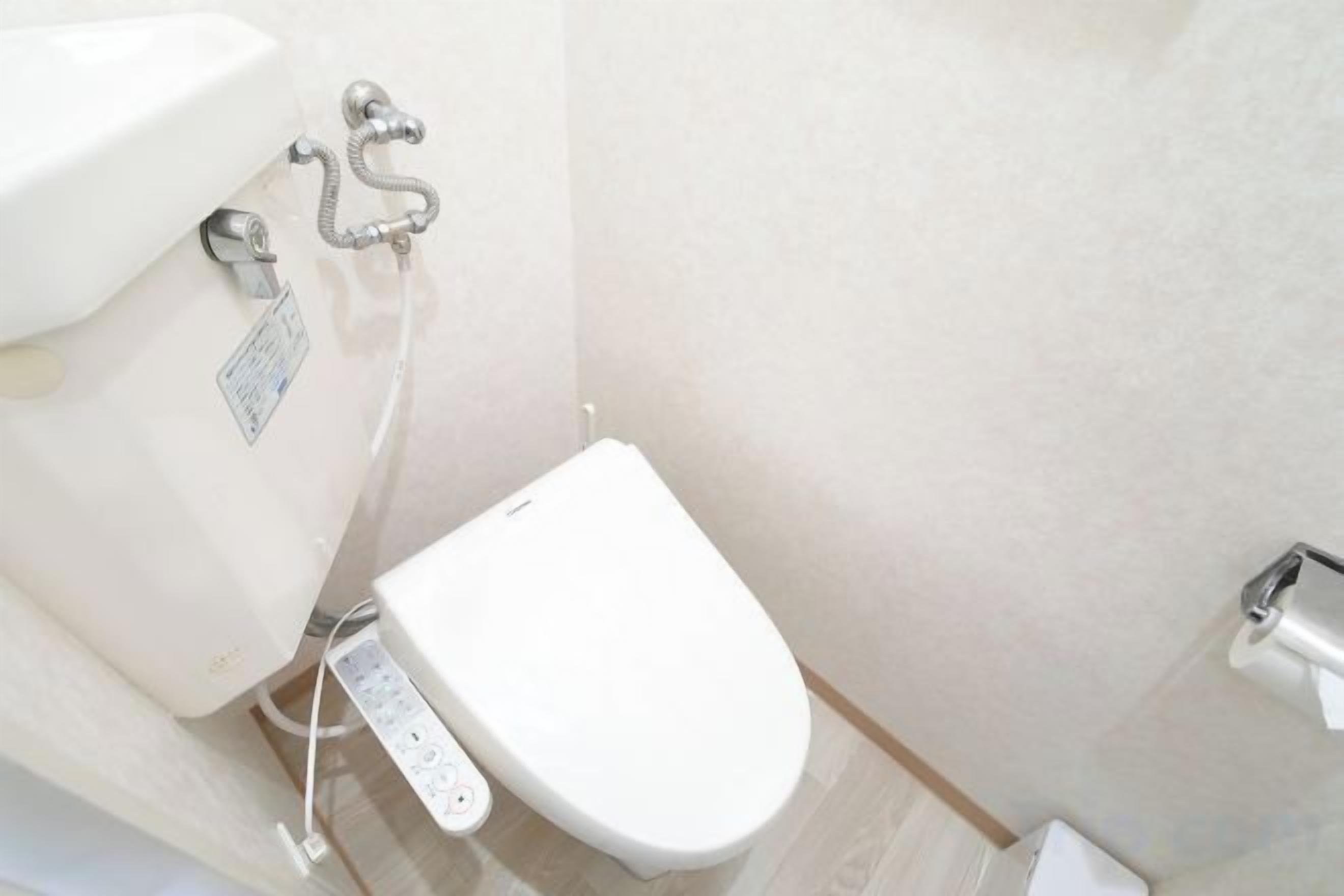 A modern bathroom with a toilet, bidet, and a wall-mounted faucet.