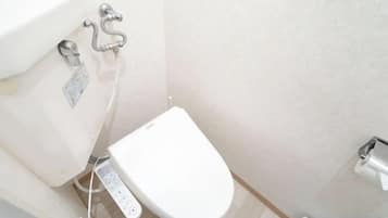 A modern bathroom with a toilet, bidet, and a wall-mounted faucet.