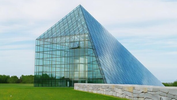 A modern glass pyramid structure with a stone base.