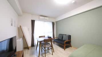 A compact living space with a television, a dining table, and a sofa.