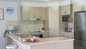Una cocina moderna con una isla central, electrodomésticos de acero inoxidable y armarios de tonos claros.