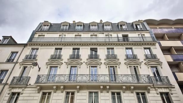 A multi-story building with a classical architectural style, featuring balconies with wrought iron railings and a symmetrical facade. - Charming Studio in the 7th District of Paris (Paris)