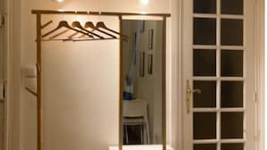 A room with a white wardrobe, a mirror, and a door with frosted glass panels. - Charming Studio in the 7th District of Paris (Paris)