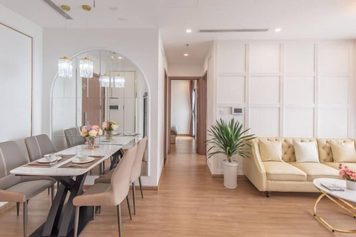 Uma sala de estar moderna com um sofá, uma mesa de jantar com cadeiras e um espelho grande.