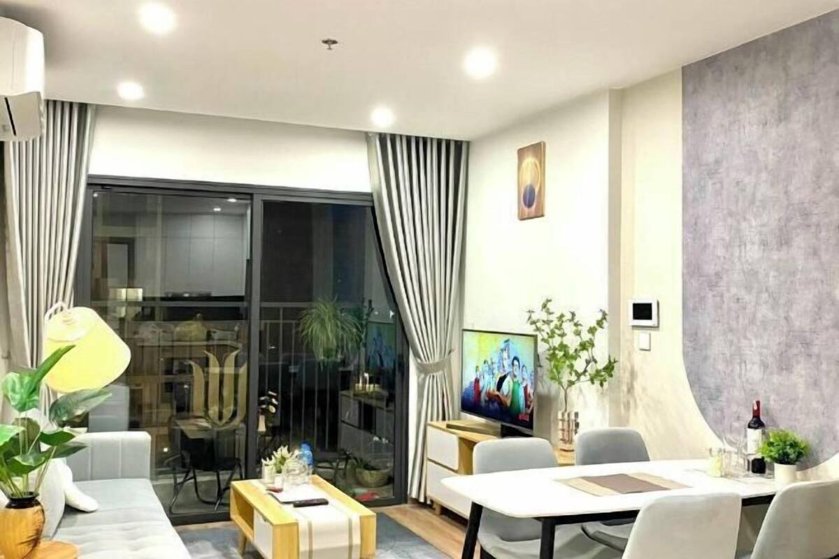 Uma sala de estar moderna com sofá, mesa de centro, televisão e área de jantar.
