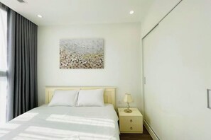 A modern hotel room with a bed, a nightstand, a lamp, and a wall art piece.