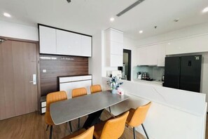 A modern kitchen with white cabinets, a black refrigerator, and a dining area with a table and chairs.