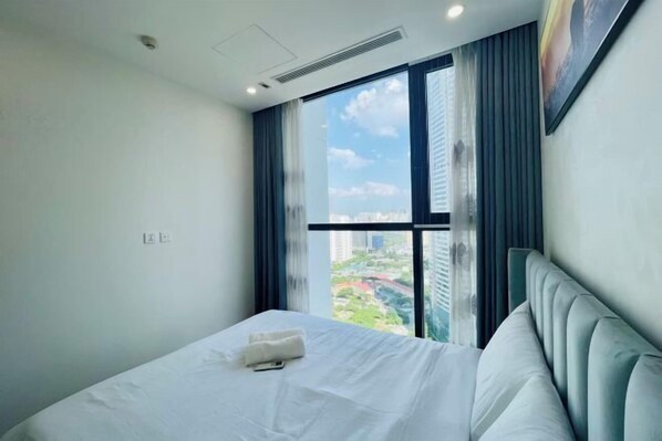 A hotel room with a large window, a bed, and a headboard.