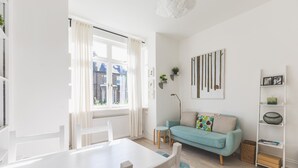 A modern living room with a white dining table, a light blue sofa, and a white bookshelf. - Stylish West London Stay by Hammersmith (London)