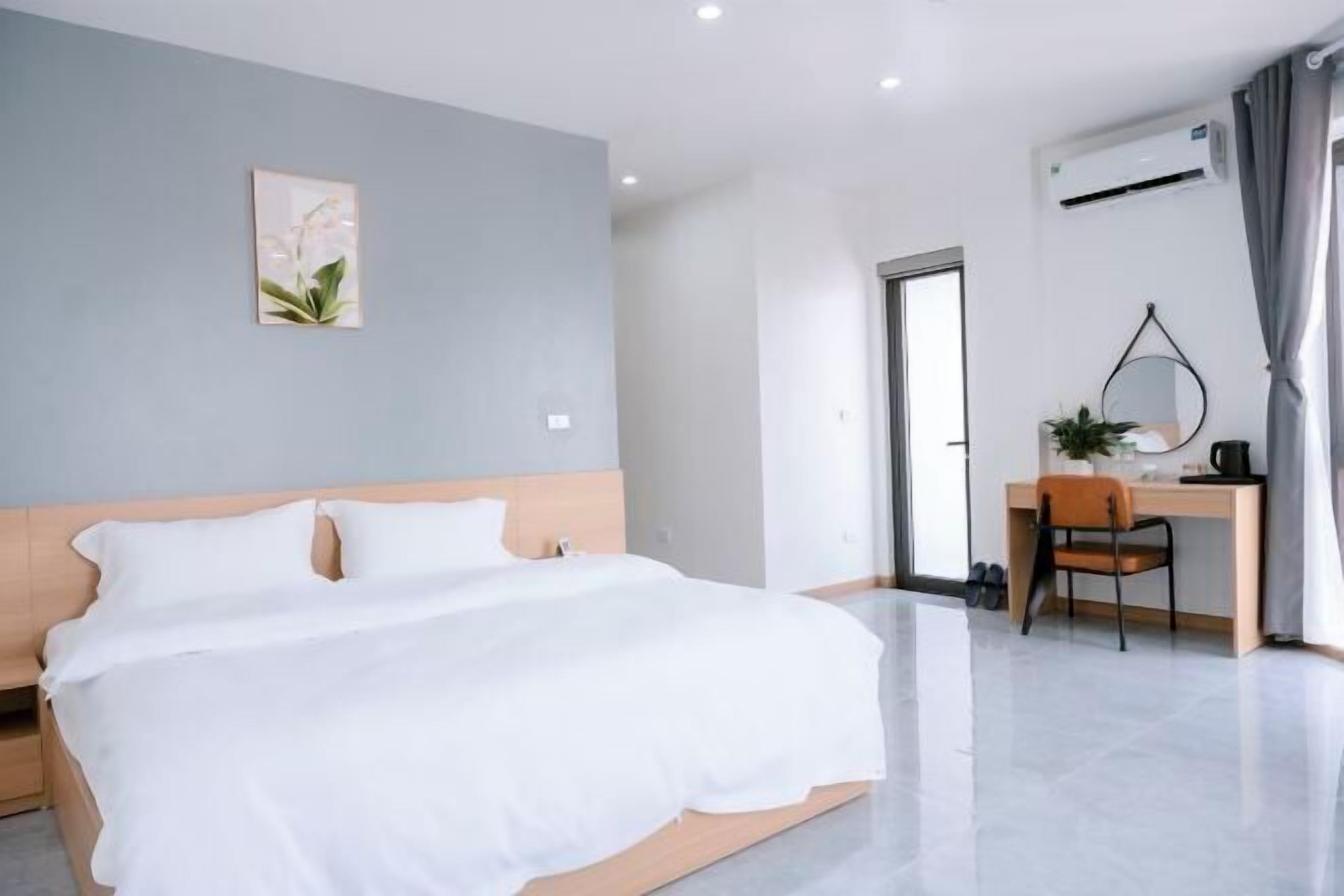 A modern hotel room with a bed, a desk, and a chair.
