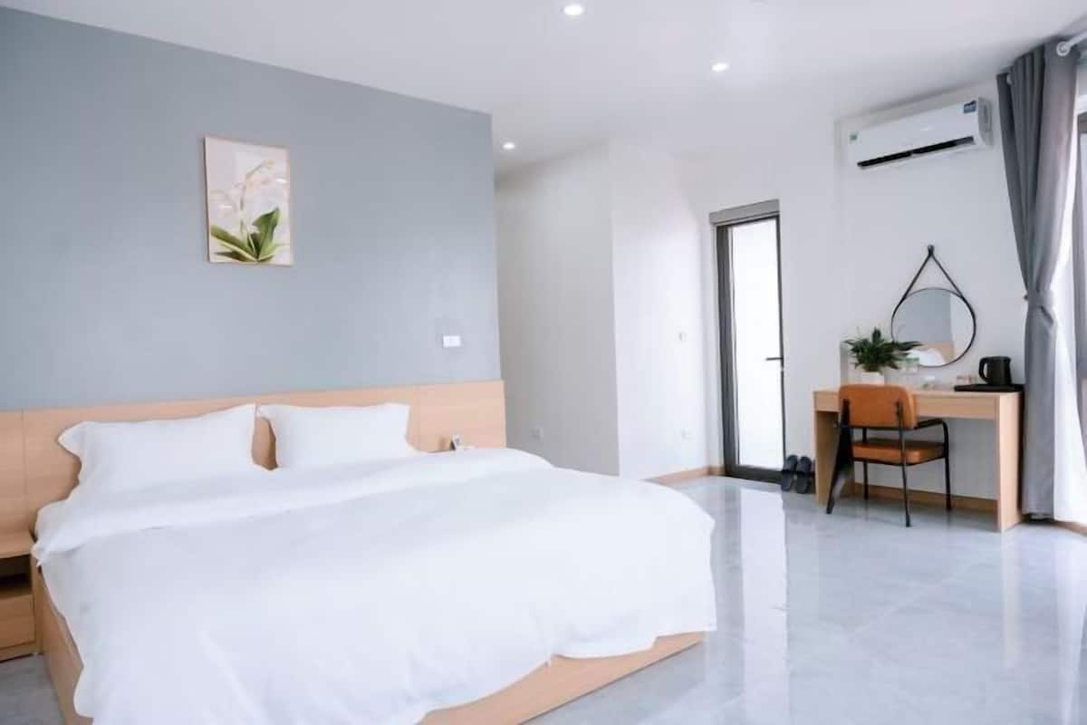 A modern hotel room with a bed, a desk, and a chair.
