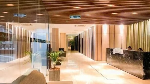 Un hall d’hôtel avec un comptoir d’accueil, un canapé et une plante en pot.
