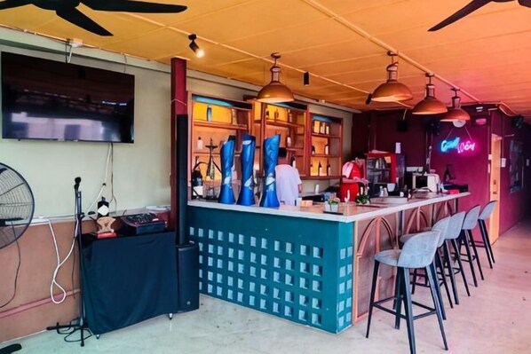 Zona de bar con mostrador, taburetes y un letrero de neón.