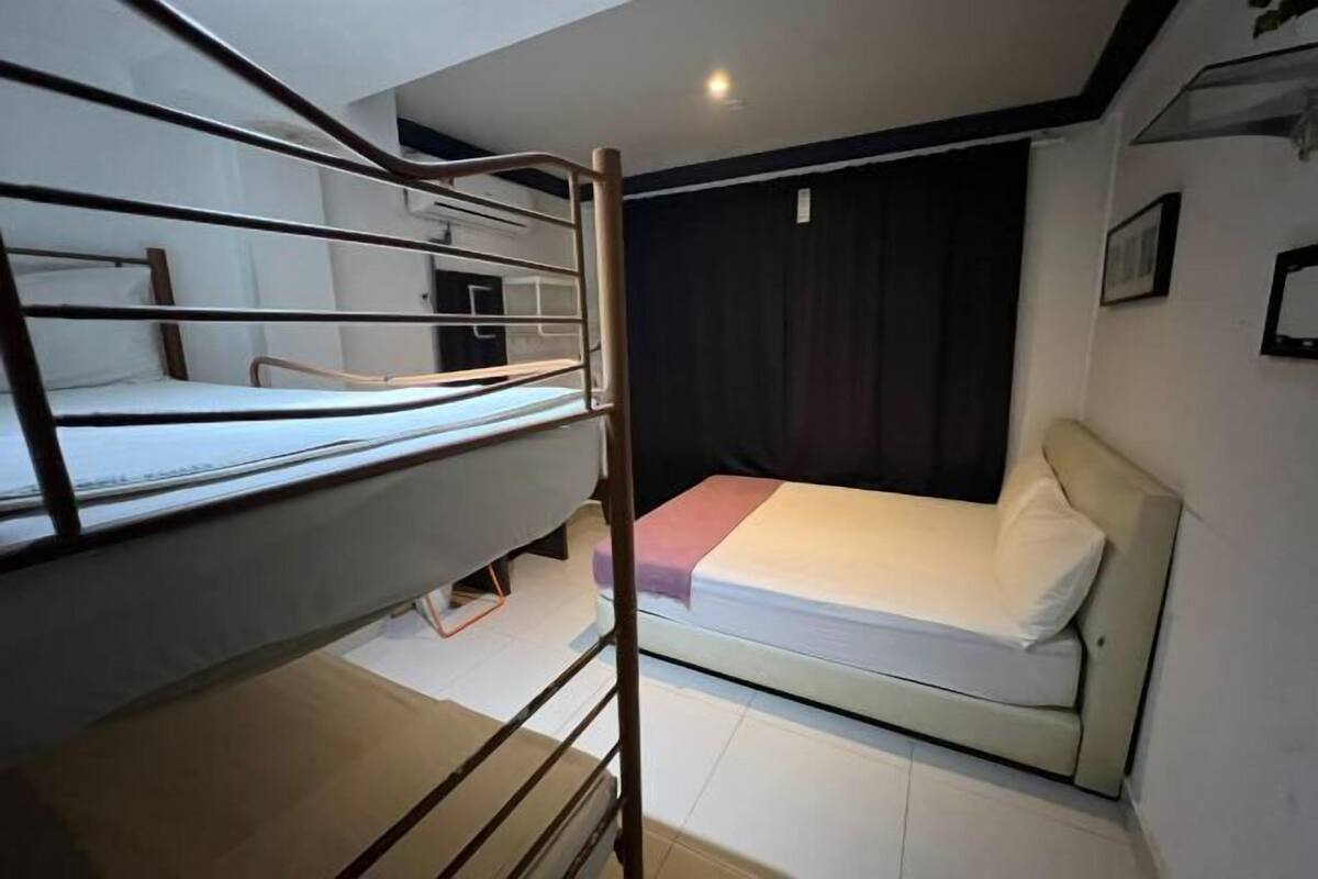 Une chambre avec un lit superposé et un lit simple, ainsi qu’une fenêtre.