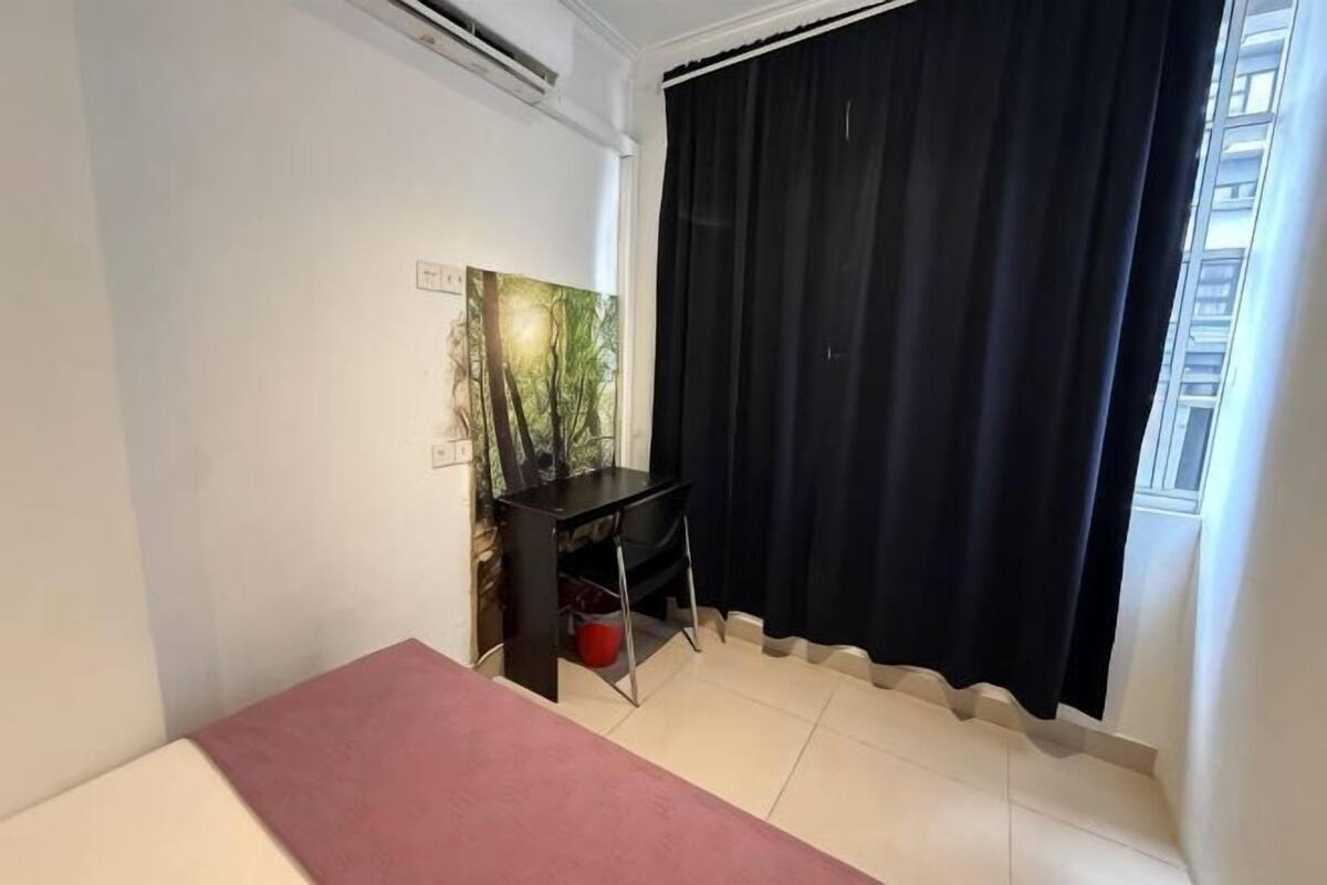 Une pièce comprenant un lit, un bureau avec un ordinateur, une fenêtre avec des rideaux noirs et un tableau accroché au mur.