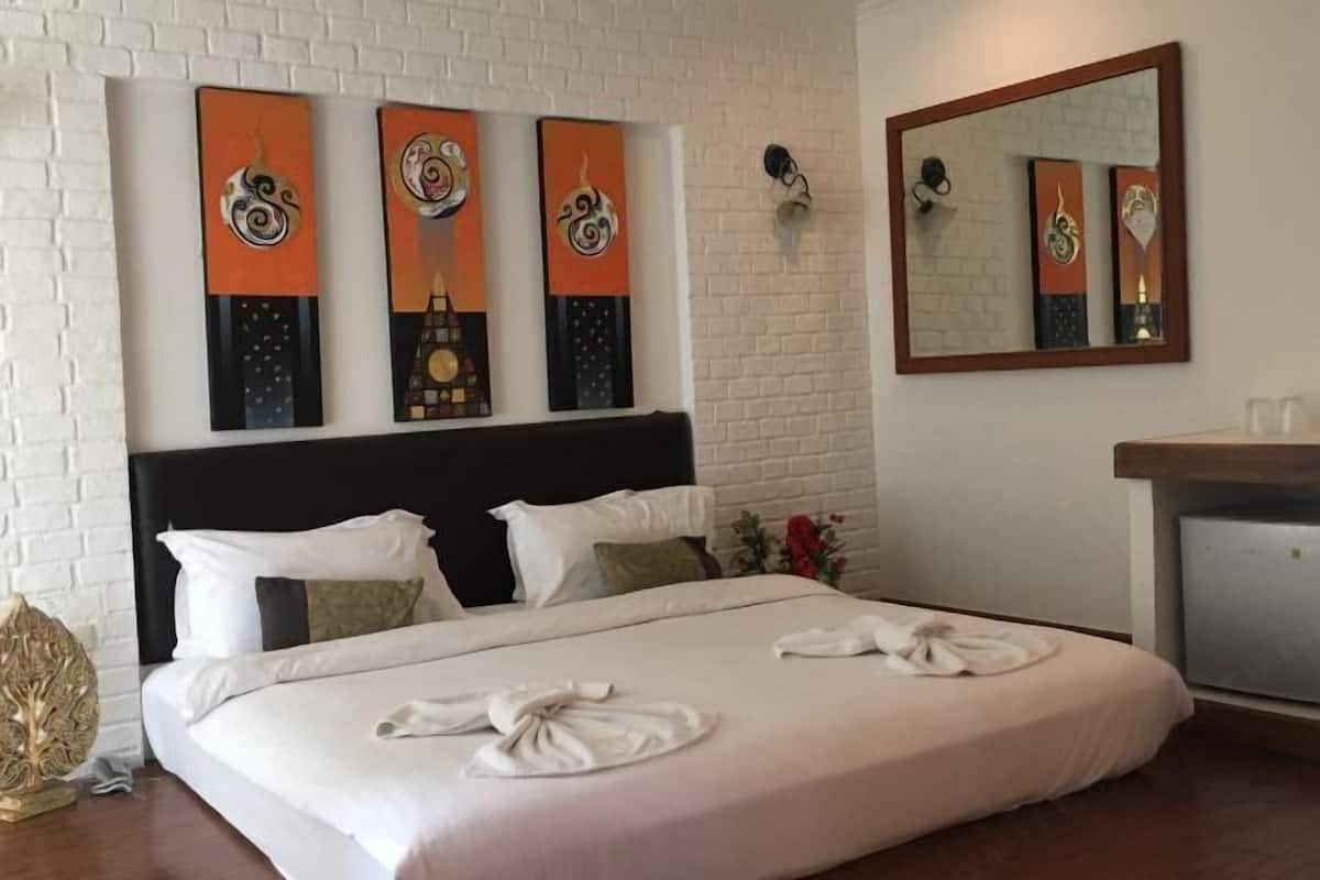 A hotel room with a bed, pillows, a nightstand, a mirror, and artwork on the wall.