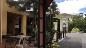Un área de estar al aire libre con mesa y sillas, un letrero de café y un edificio con fachada verde.
