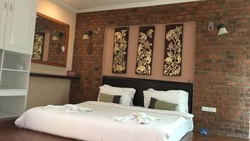 A hotel room with a brick wall, a bed with white bedding, a headboard, and a wall-mounted light fixture.
