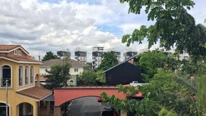 Zona residencial con un coche rojo aparcado en una entrada, rodeada de vegetación y casas.