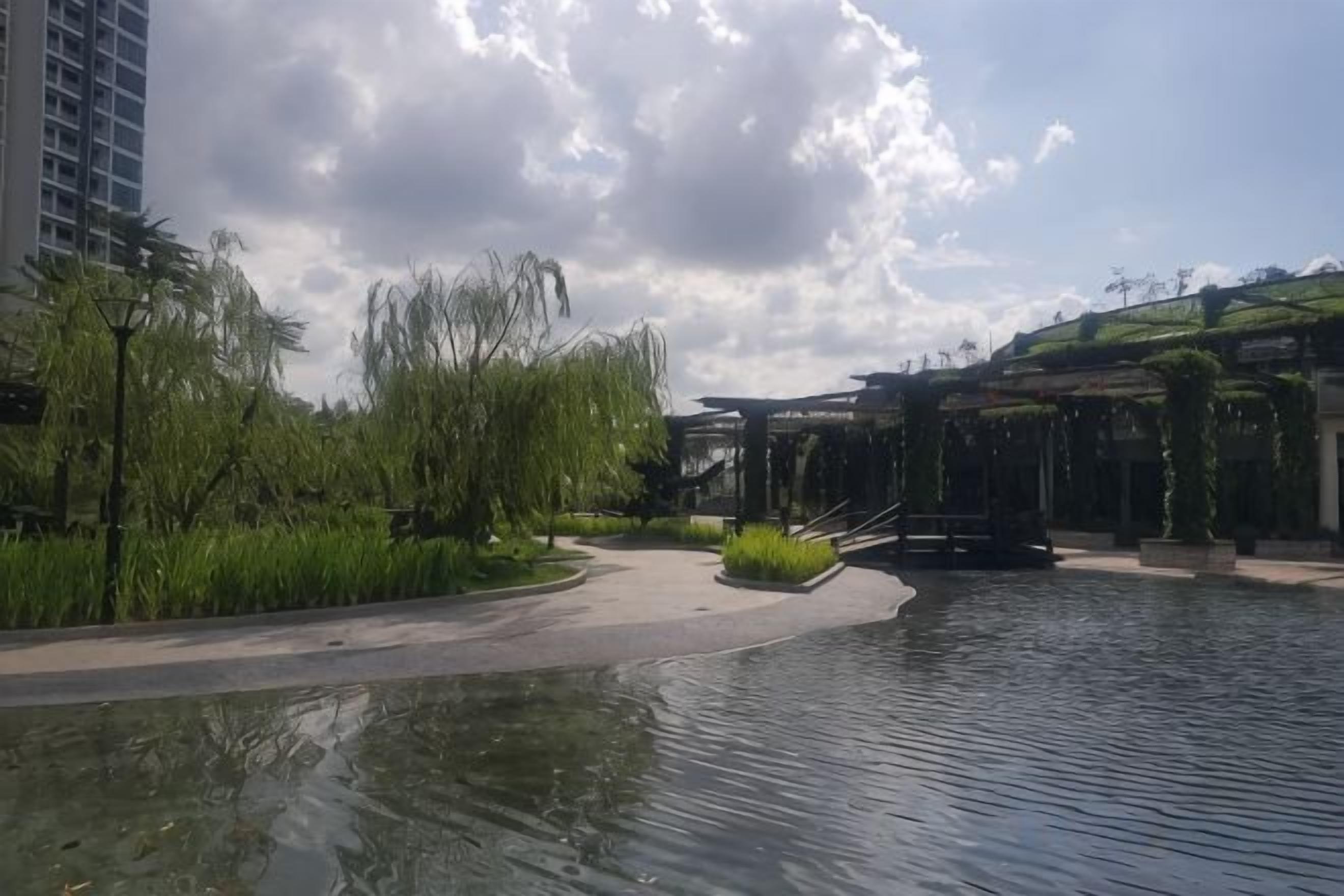 A water feature with a pathway, greenery, and a building with a modern design.