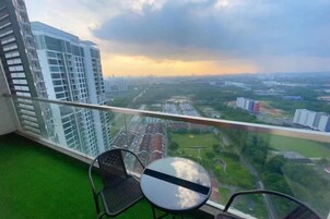 A balcony with a view of a cityscape, a table, and two chairs.