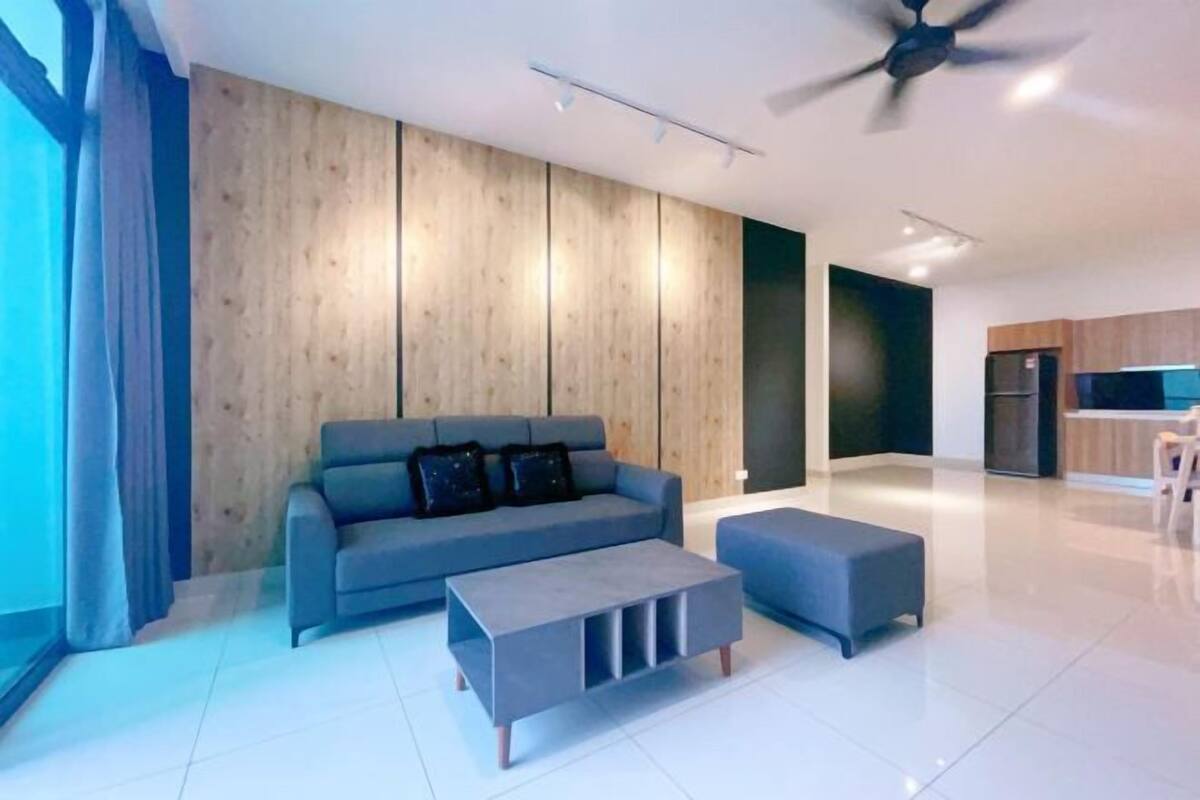 A modern living room with a sofa, ottoman, and a ceiling fan.